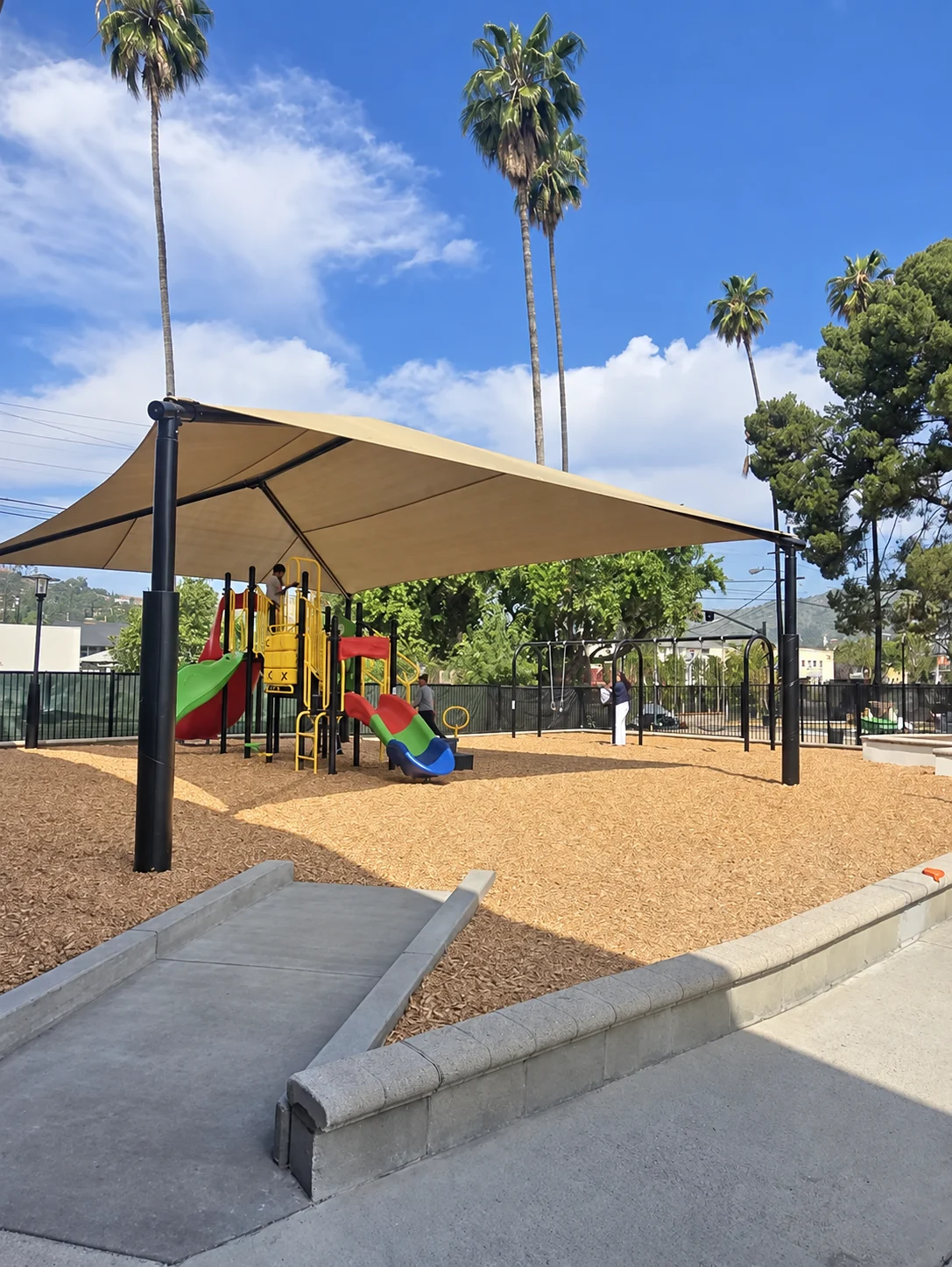 WCC's outdoor play area with a large shade canopy, climbing structures, and slides